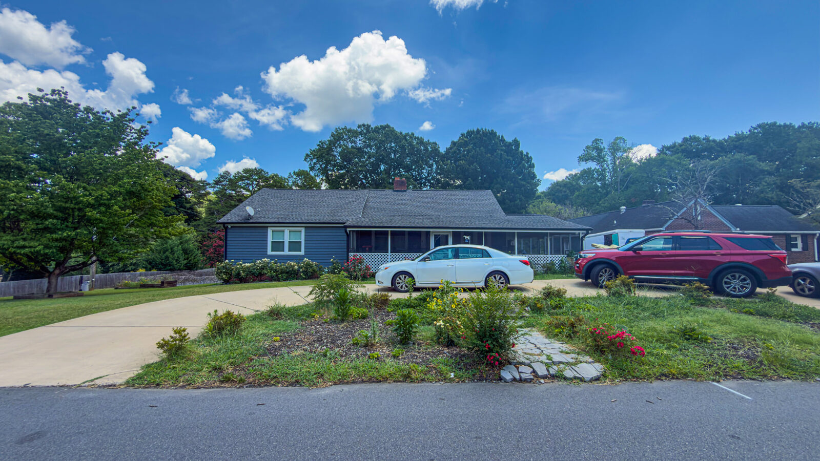 Navy ranch-style home with a screened porch and circular driveway in North Carolina