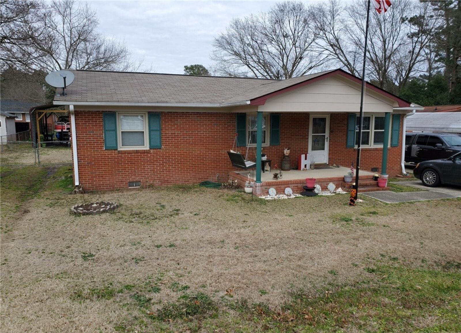 Brick ranch home with teal shutters, a covered front porch and a large front yard