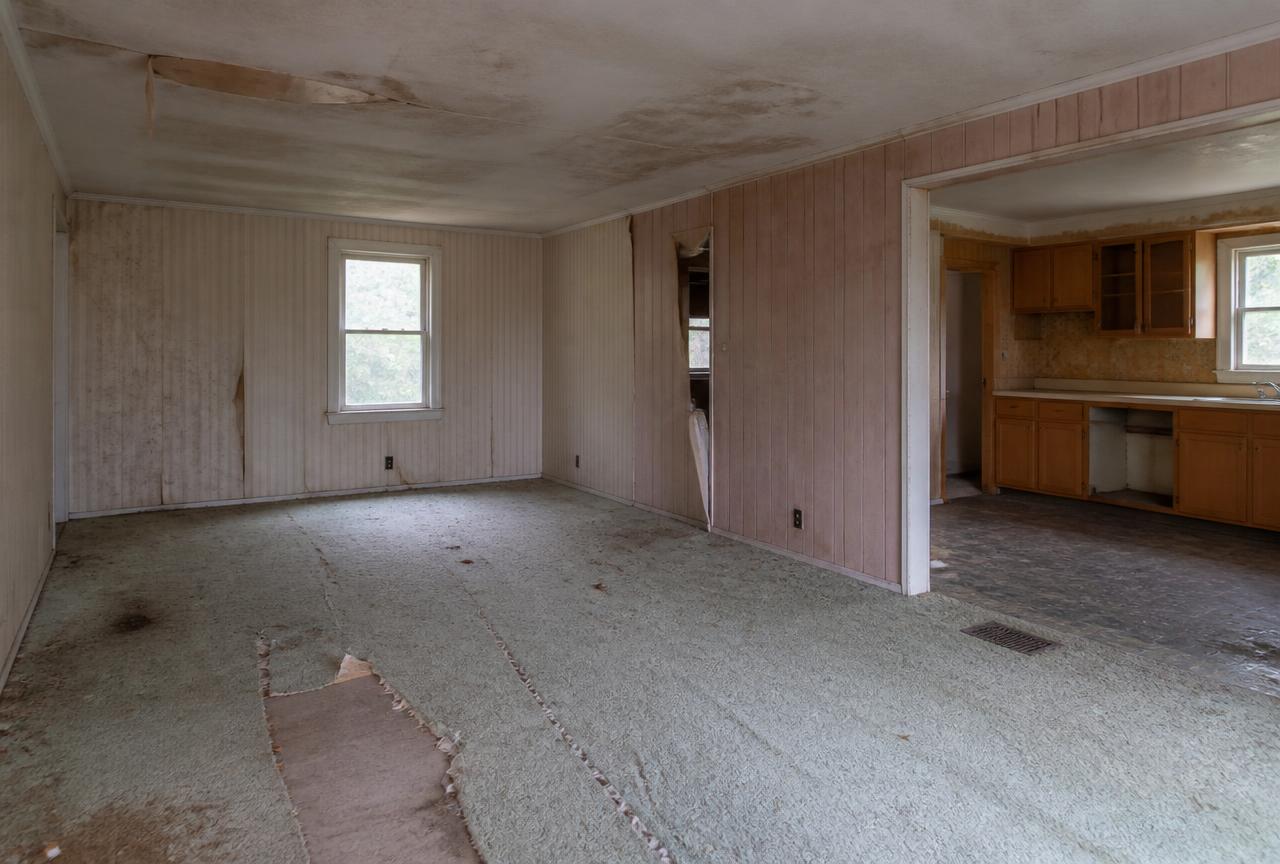 Interior of an outdated house with water-stained ceiling and torn carpet